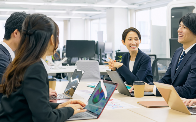 3人の社員がオフィスで笑顔で話している写真